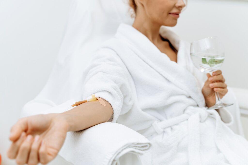 Close up of calm female patient sitting with tube and needle during IV infusion.